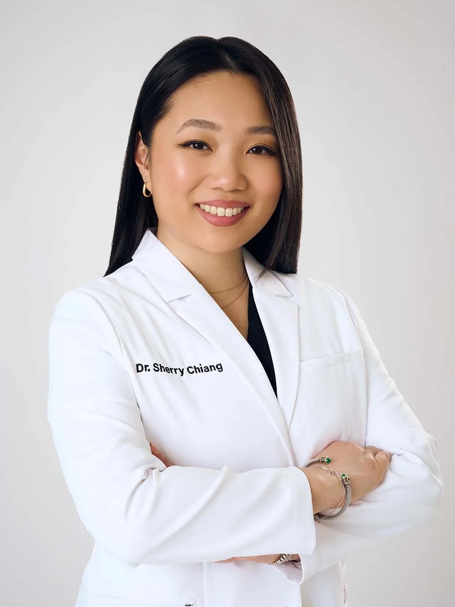 A professional woman with long dark hair smiling, wearing a white coat with the name tag 'Dr. Sherry Chiang', standing against a plain light background.
