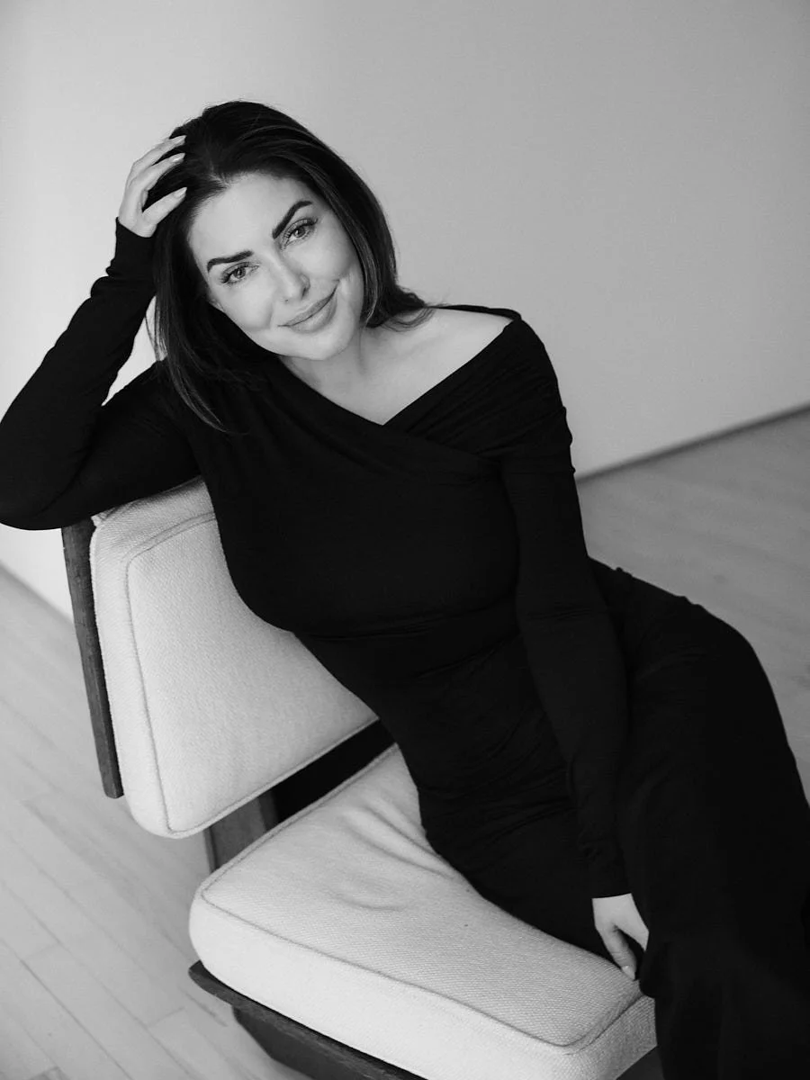 Black-and-white portrait of a woman leaning on a pale sofa.