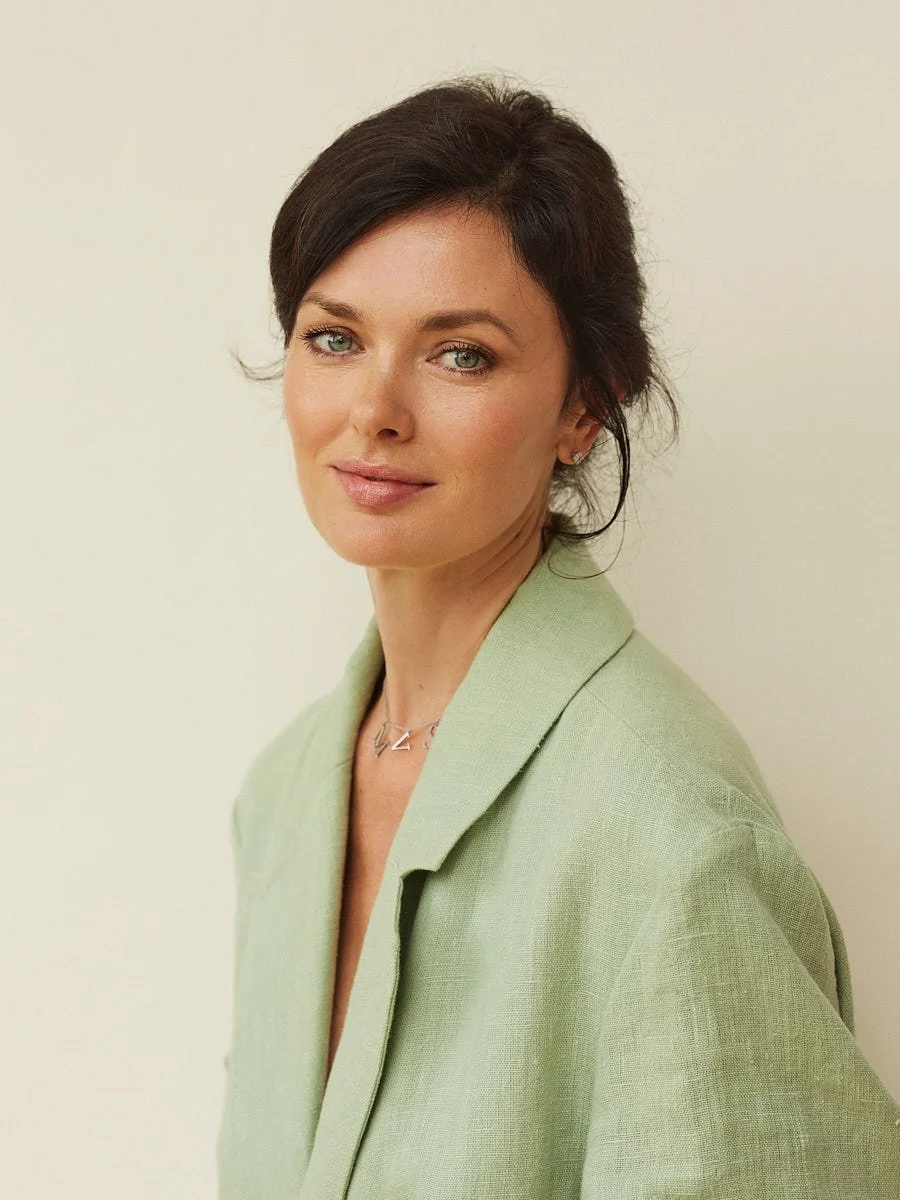 Woman in a light green blazer against a pale background.