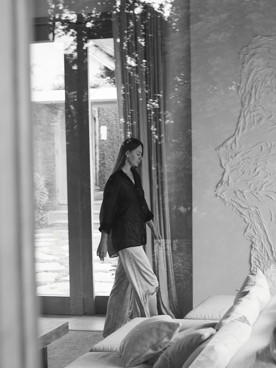 Black-and-white photograph of a woman walking through a glass doorway.