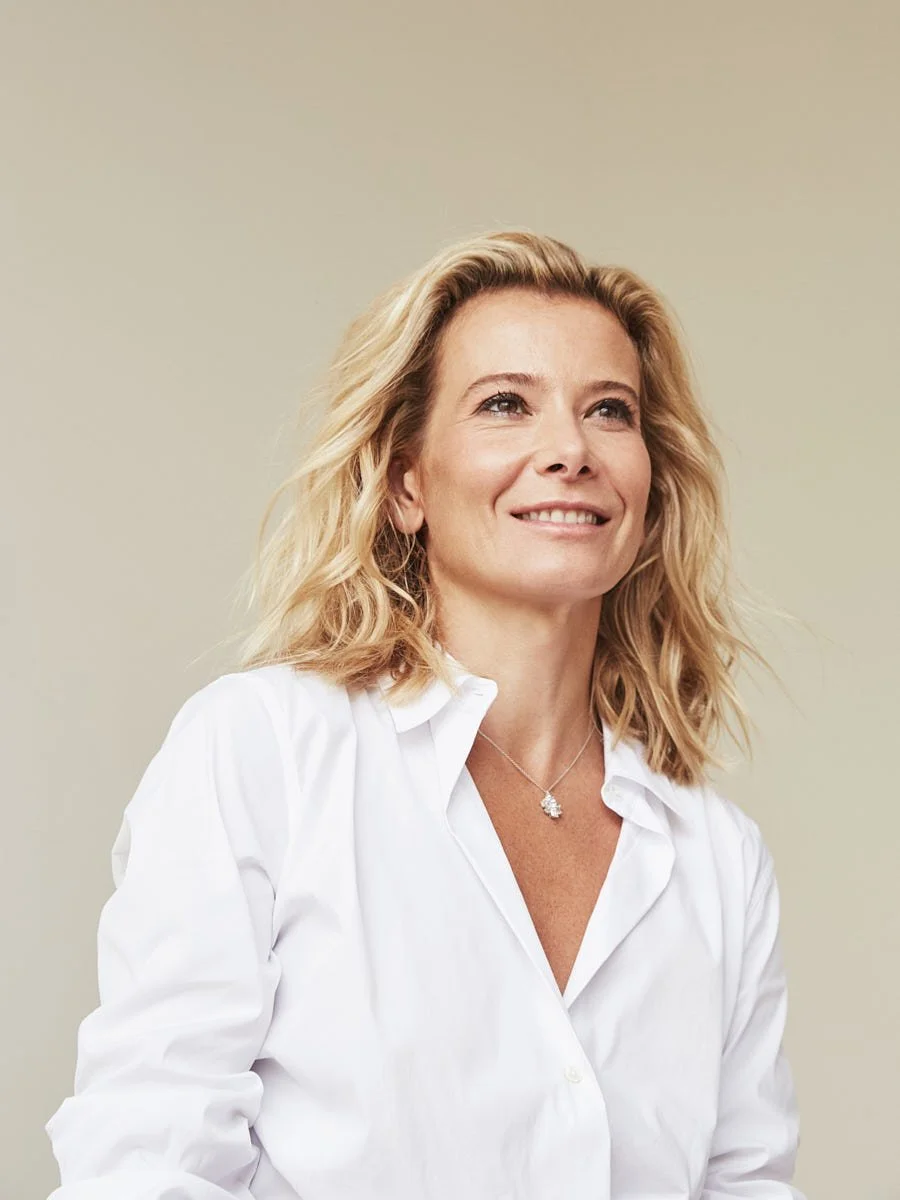 Woman in a white shirt looking upward against a pale background.