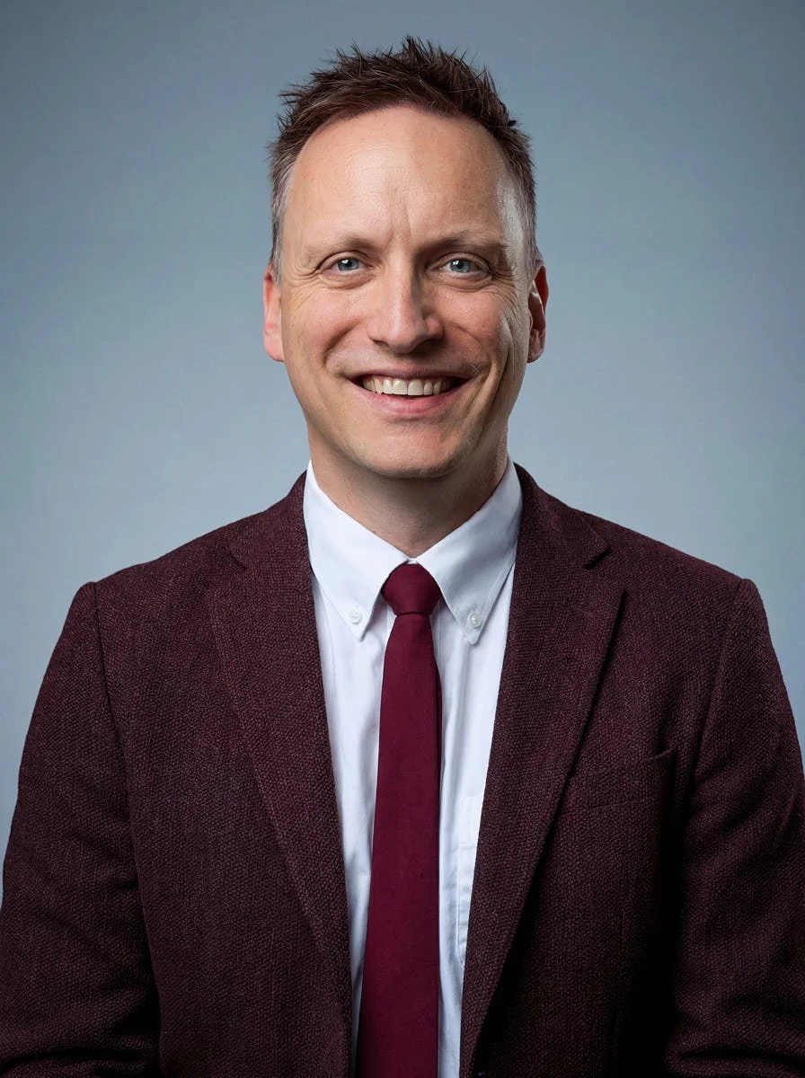 Remote team portrait in a burgundy jacket against a blue-gray background.