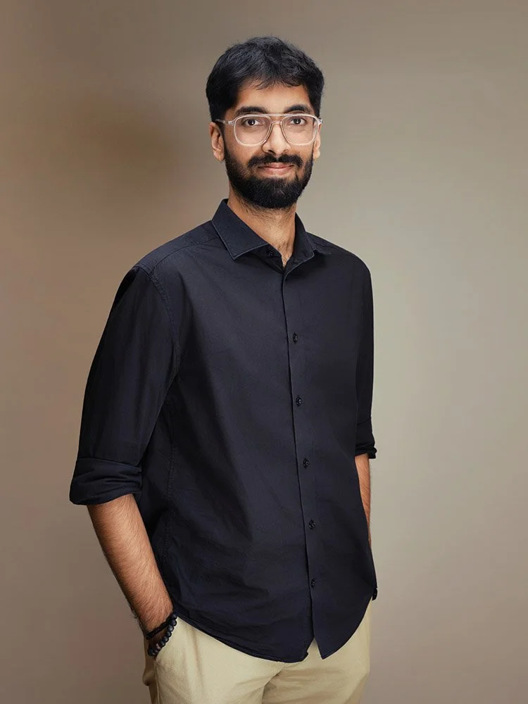 Person wearing glasses and a dark shirt against a light background.