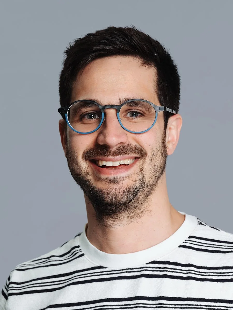 Head-and-shoulders portrait of a person wearing glasses and a striped shirt.