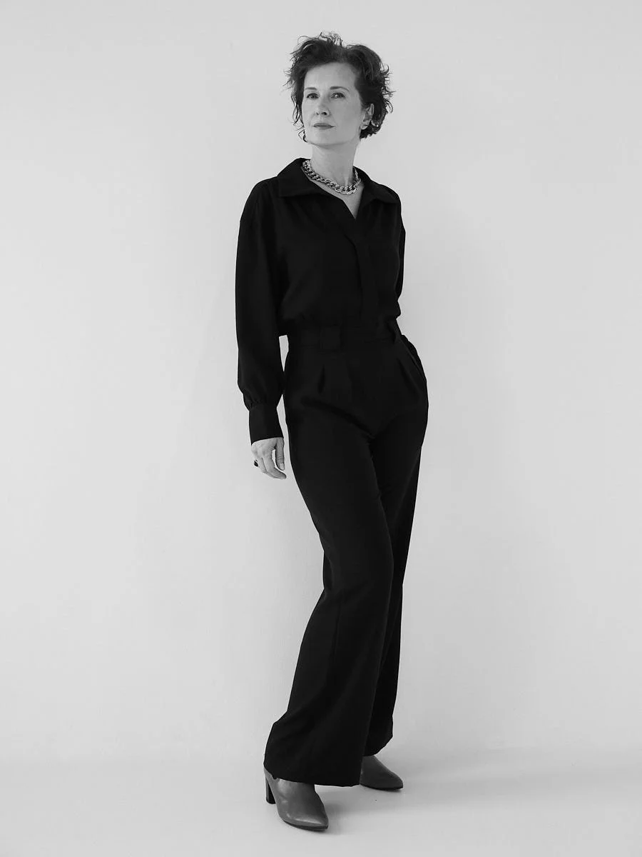 Full-length black-and-white portrait of a woman in a dark outfit.
