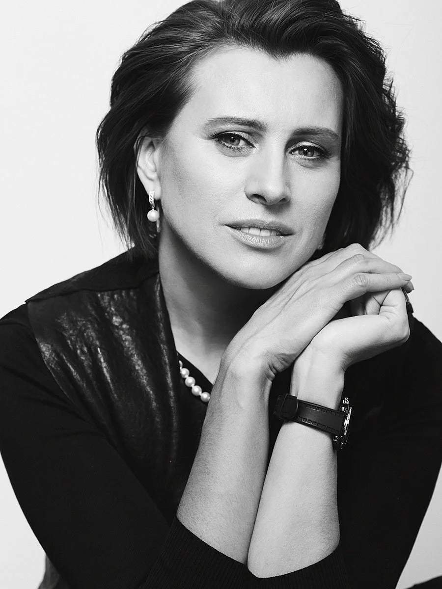 Black-and-white close portrait of a woman with her hands near her chin.